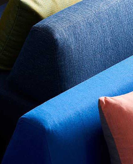 a light blue and dark blue cushion with the corner of an orange cushion visible