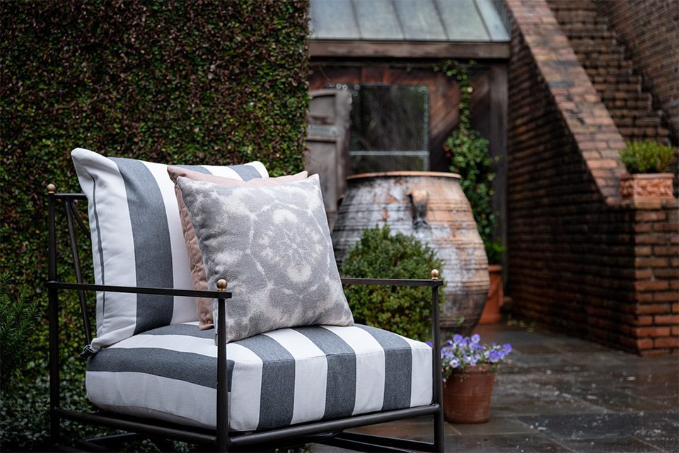 A patio chair with striped fabric and pillows outside