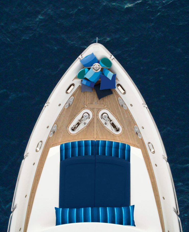 woman relaxes on a couch on a boat and holds a drink