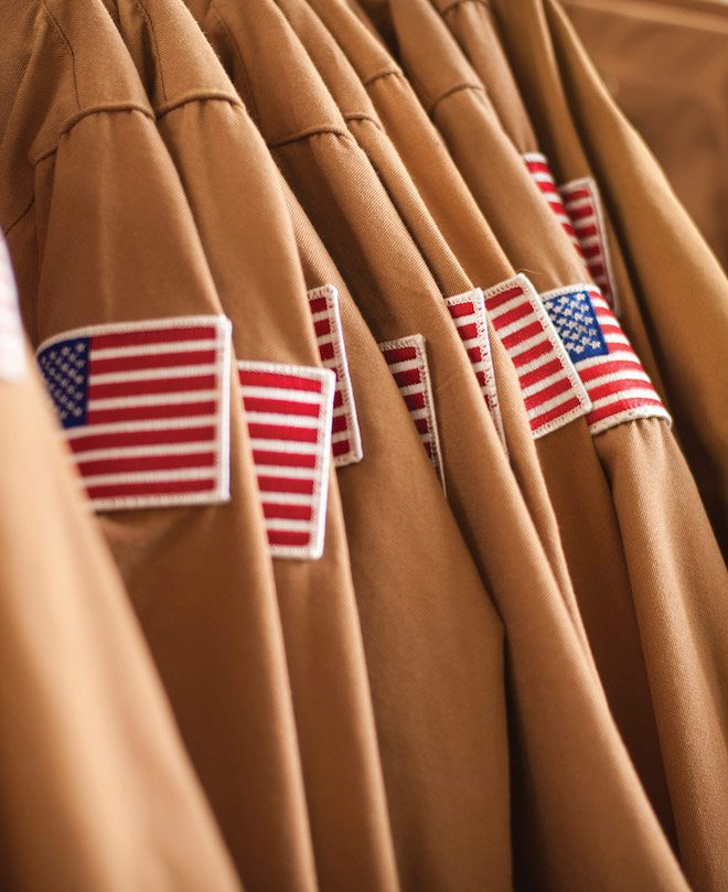 several brown military uniforms with american flags on the sleeves
