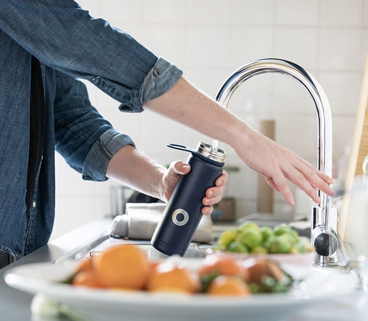 person filling a water bottle at a stainless steel faucet