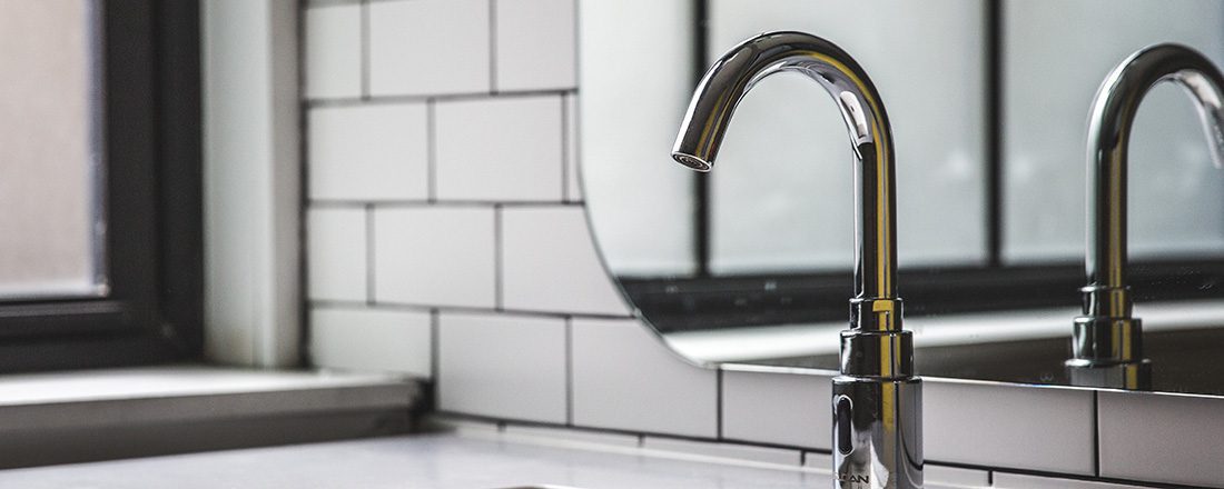 a stainless steel faucet with a mirror behind it