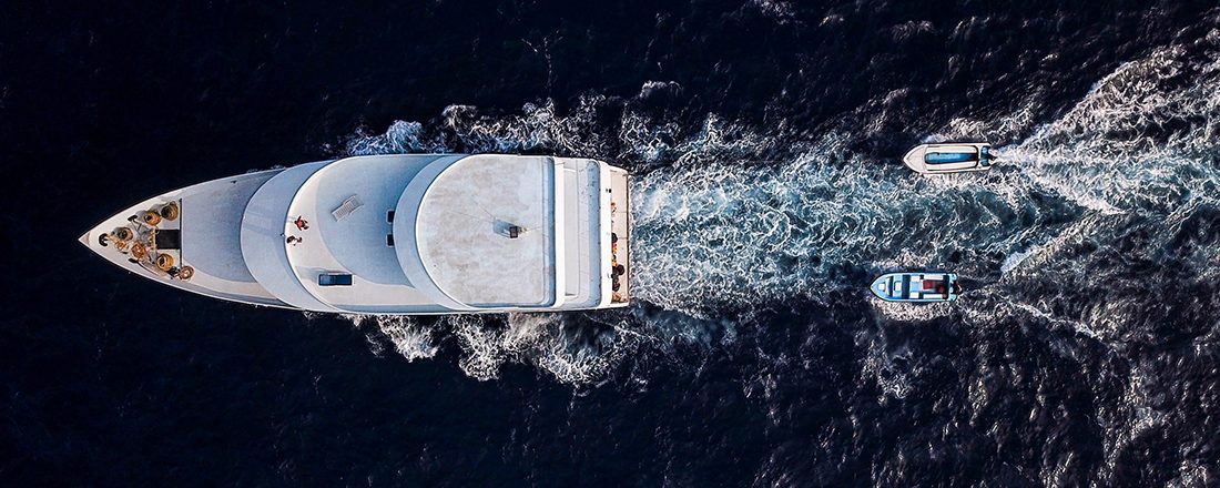 aerial shot of luxury boat trailed by two smaller boats