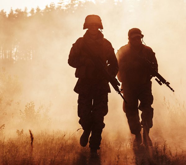 two armed soldiers walk through the mist