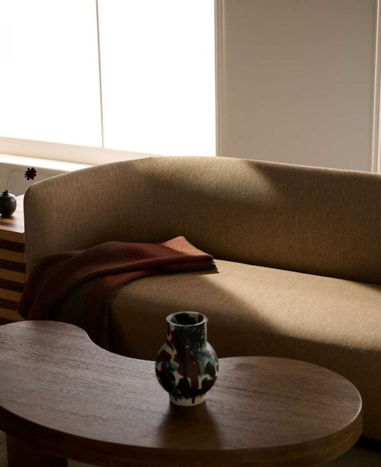 a wooden stool with a couch, cushions, and blankets in the background