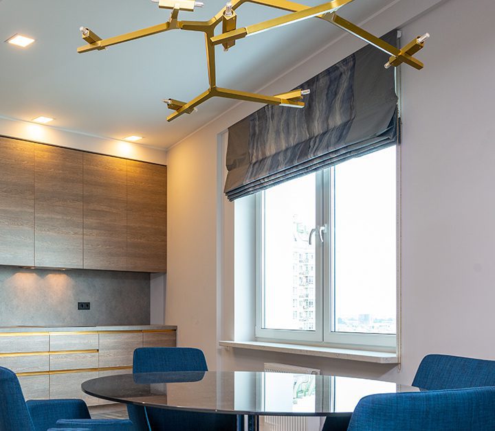 sitting area with blue chairs and a table beneath gold light fixture