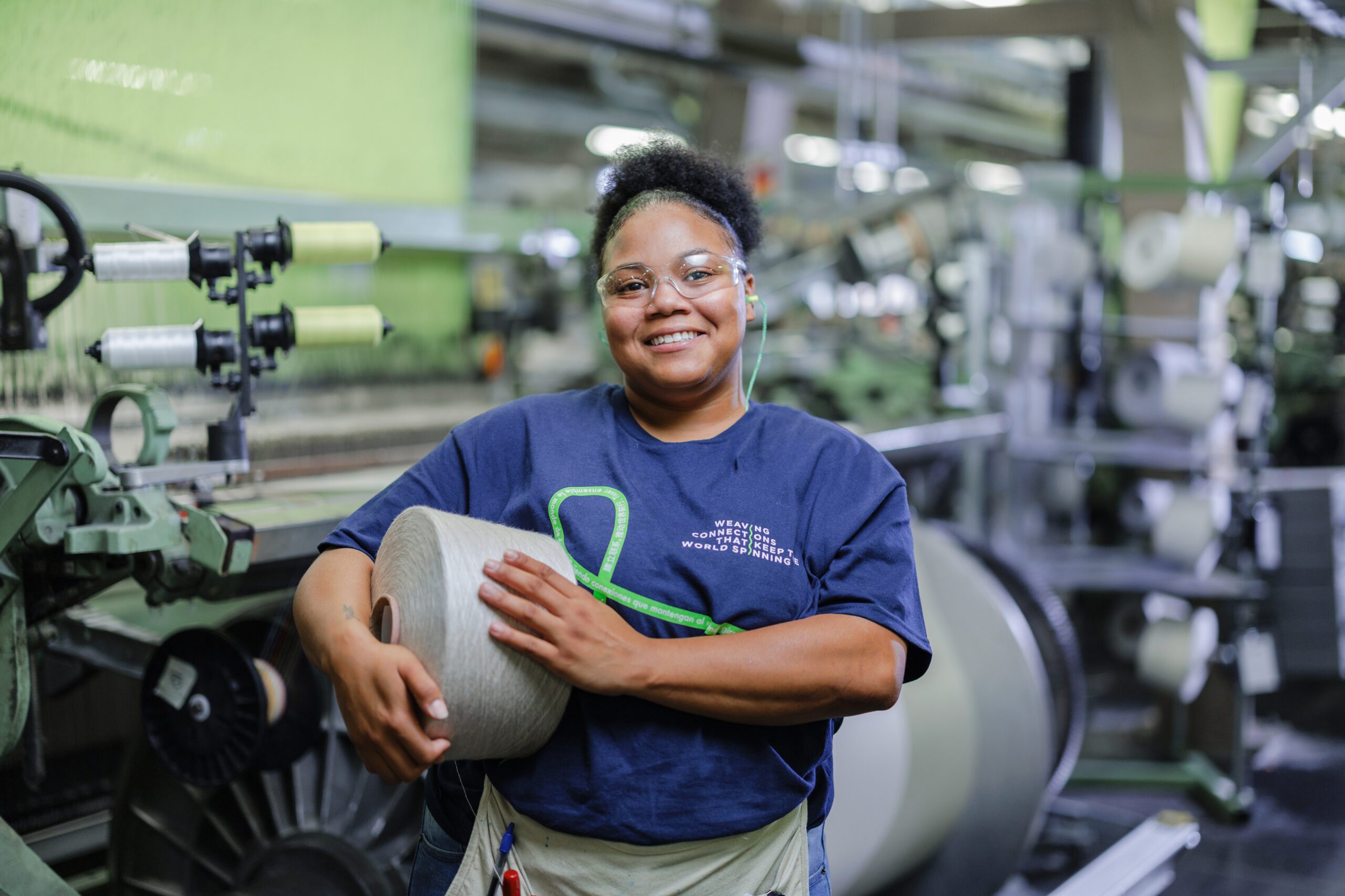 a Glen Raven employee smiles and holds a large spool of thread