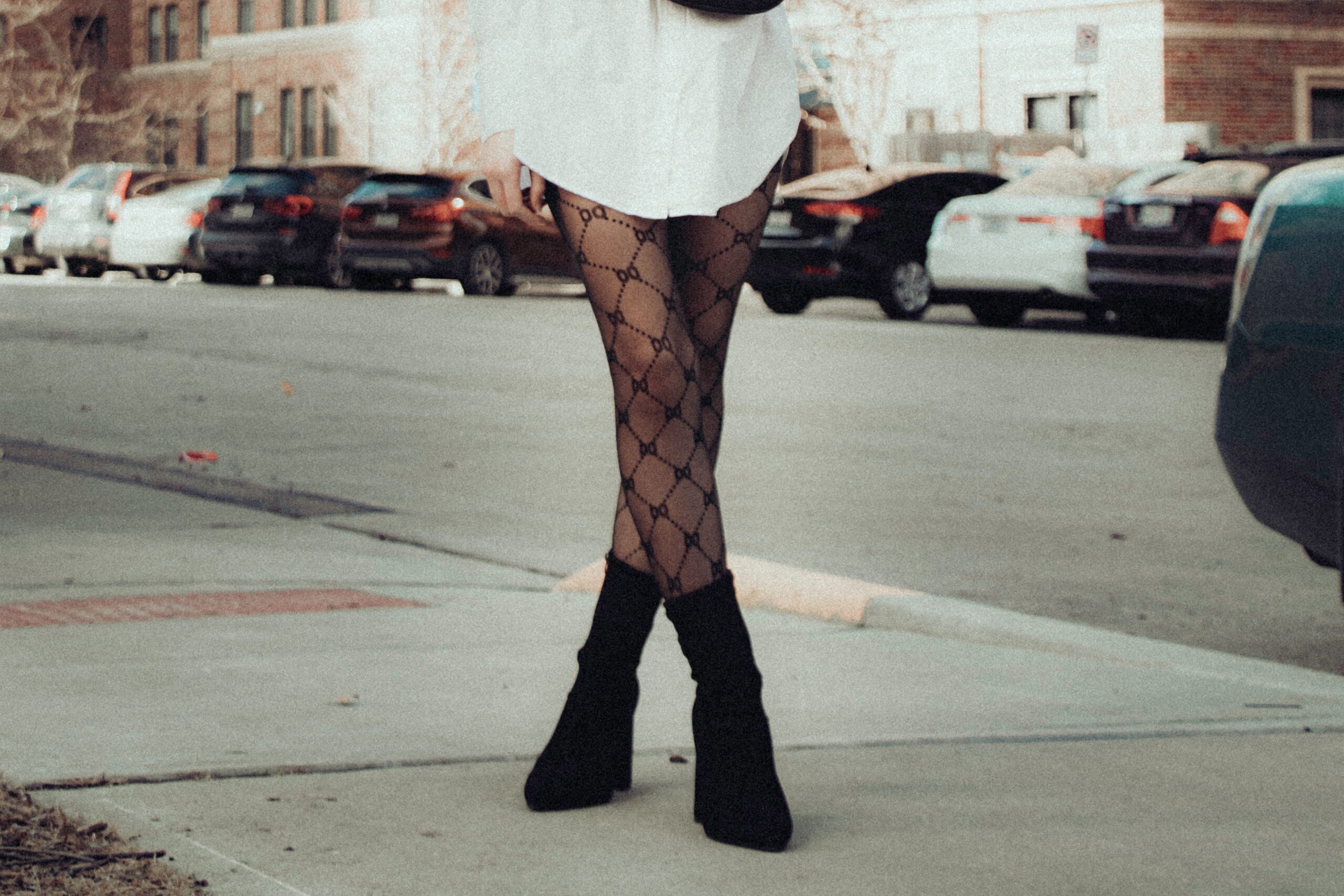 a woman standing on a sidewalk in sheer black tights