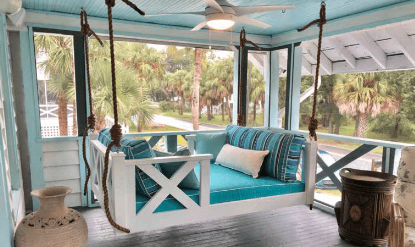 a hanging porch swing on a screened in porch with blue striped cushions