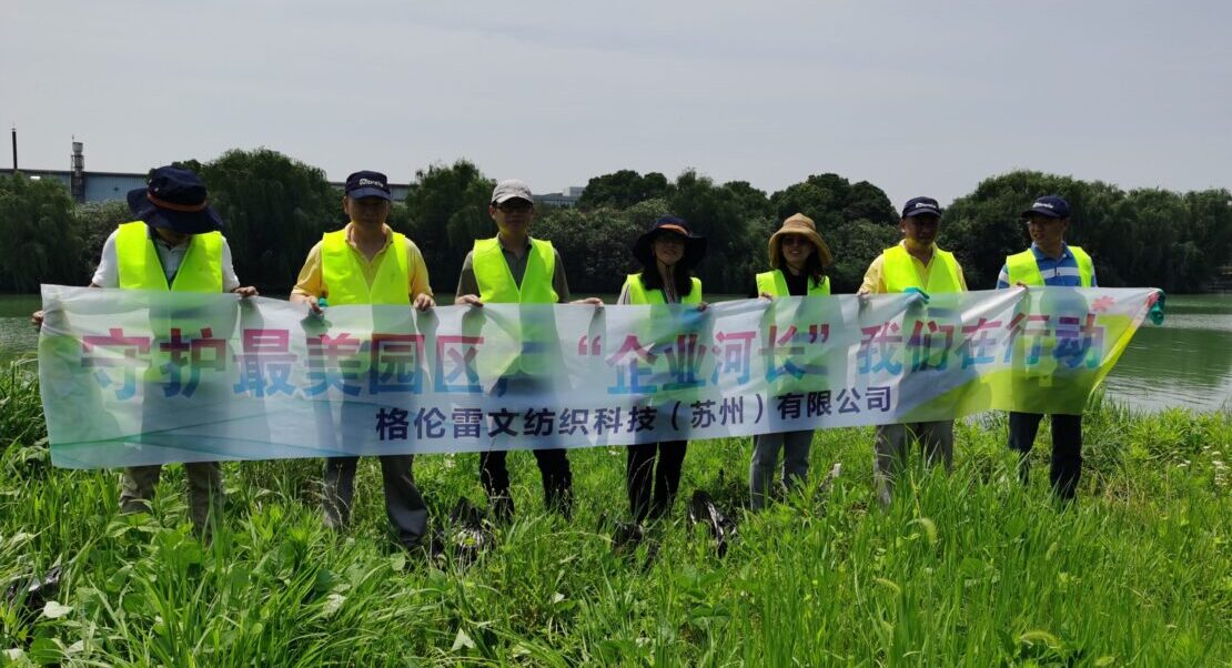 Glen Raven Asia employees hold a banner and stand beside a river