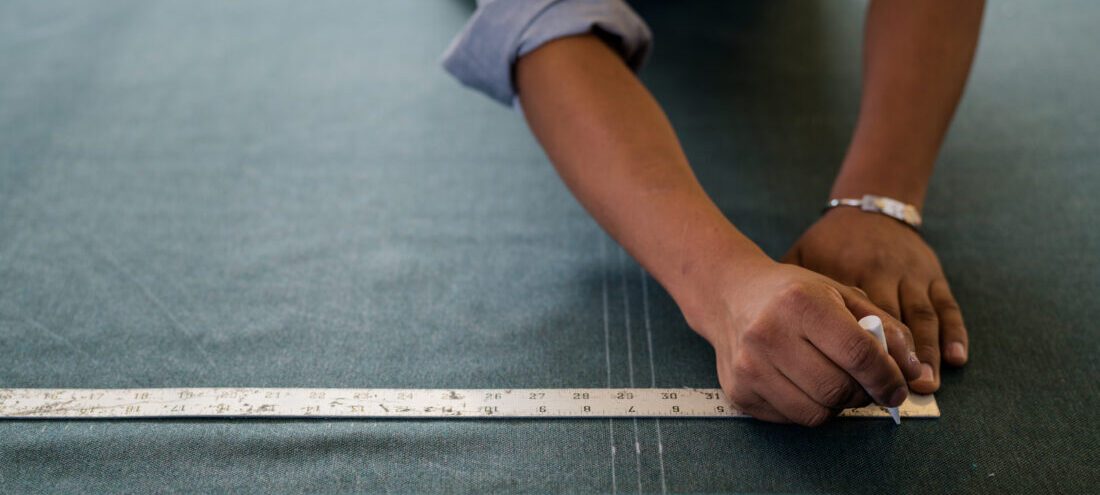 Someone uses a ruler to measure marks on fabric