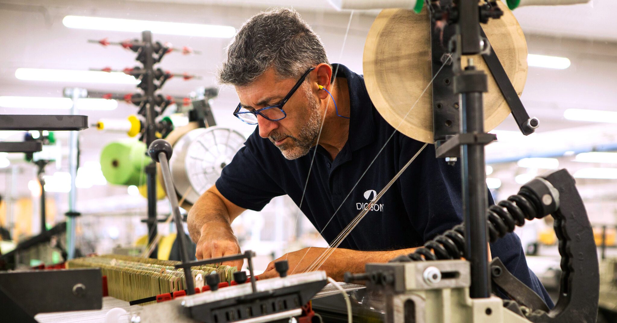 man working with thread in a fabric machine